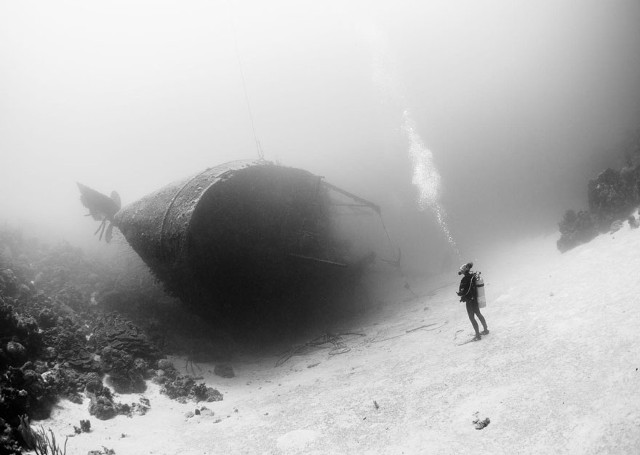 Foto hitam putih, dengan objek foto bangkai kapal yang terletak di pulau Karibia. (kredit foto: National Geographic/Marc Heauer)