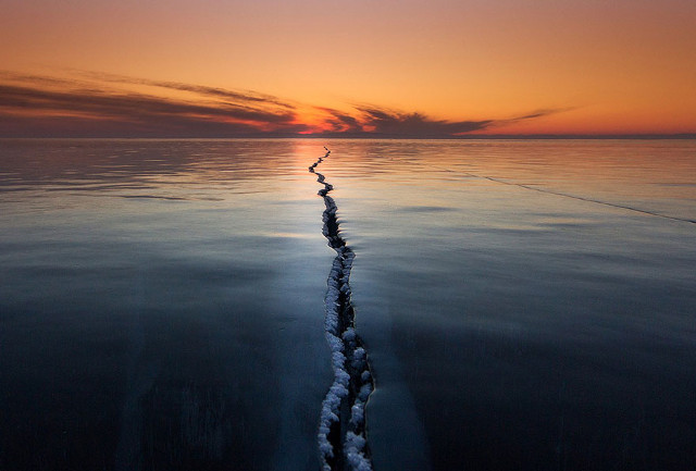 Sebuah fenomena alam di Rusia yang menakjubkan terjadi di Danau Baikal setiap tahun selama bulan Maret. Pergeseran suhu, angin, es, dan sinar matahari menyebabkan permukaan danau beku retak. (kredit foto: National Geographic/Alexey Trofimov)