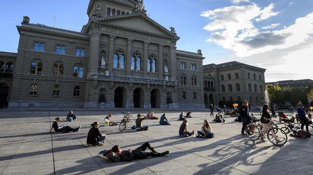 Warga Swiss bersantai di depan Gedung Parlemen.