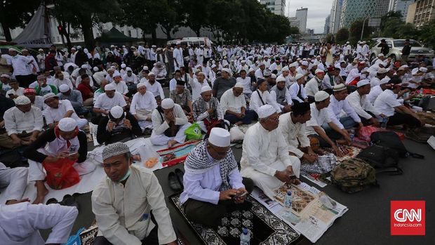 Massa duduk menggelar sajadah sembari membaca doa.