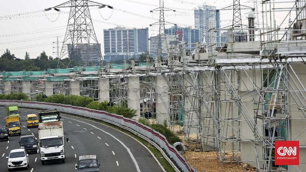 Sejumlah kendaraan melintas di samping pembangunan tiang penyangga jalur transportasi light rail transit (LRT) Cibubur-Cawang di Jakarta, Selasa, 10 Januari 2017. (CNN Indonesia/Adhi Wicaksono)