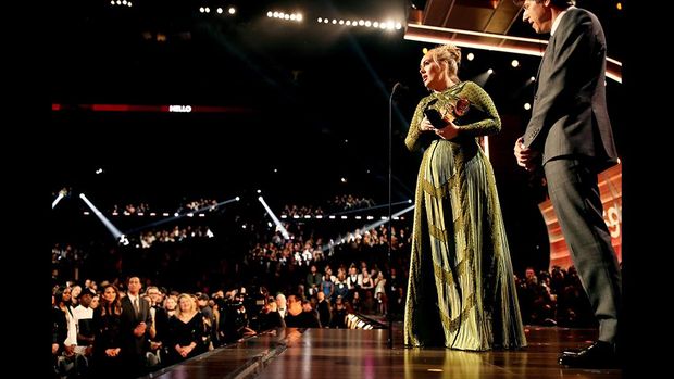 Adele saat menerima penghargaan di atas panggung.