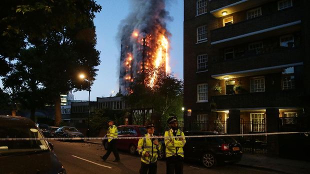 Polisi memasang garis keamanan di sekeliling apartemen yang terbakar di Kensington, London.