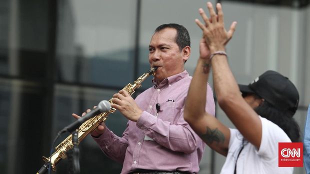 Wakil Ketua KPK Saut Situmorang dengan flute mengiringi Slank, di halaman kantor KPK, Jakarta, Kamis (13/7). Ia menyebut, korupsi akan tetap merajalela jika tak ada dukungan Pemerintah melalui rencana pemberantasan korupsi yang jelas.