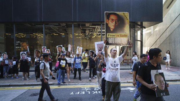 Demonstran pro demokrasi di Hong Kong mengacungkan foto pemenang Nobel Perdamaian Liu Xiaobo dan istrinya Liu Xia dalam sebuah aksi protes di Hong Kong, Juni lalu.
