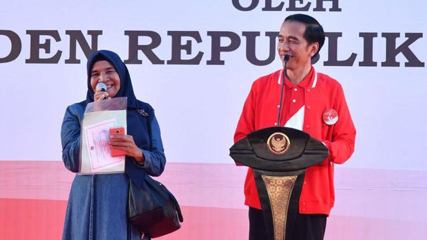 Jokowi membagikan sertifikat tanah, ada pin di jaketnya.