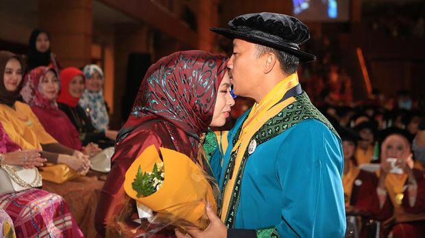 Menpora Imam Nahrawi mencium sang istri usai wisuda S2.