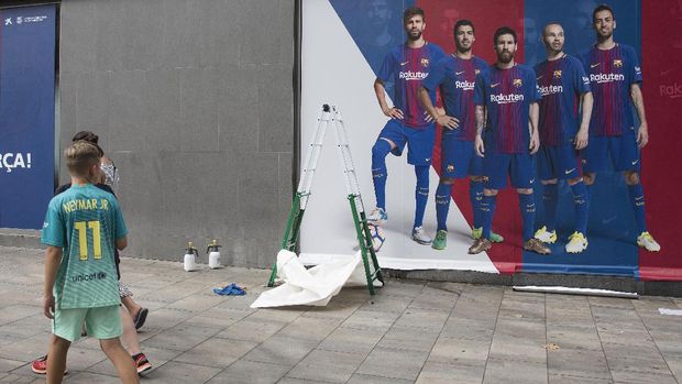 Suporter cilik menggunakan kostum Neymar melihat poster di Camp Nou.
