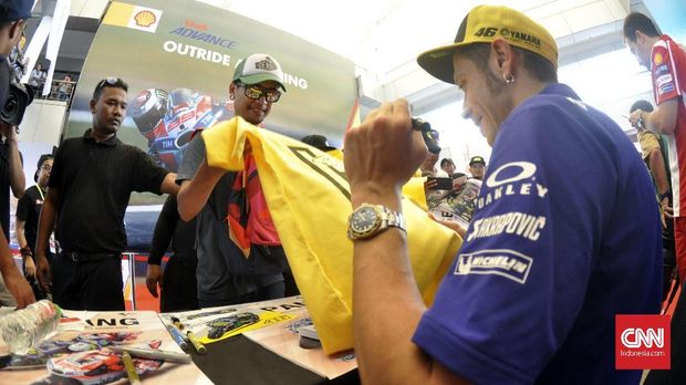 Para penggemar langsung menyorongkan kaus meminta tanda tangan Valentino Rossi. (