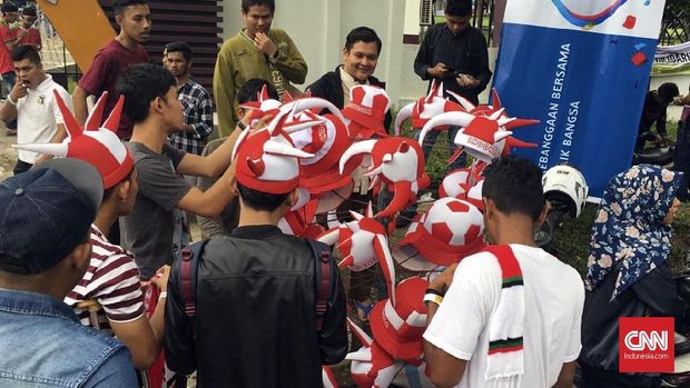 Suporter Indonesia tengah membeli atribut Timnas Indonesia.